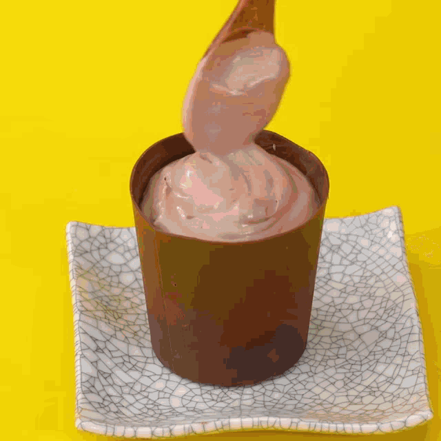 a person is holding a strawberry over a chocolate cup of ice cream
