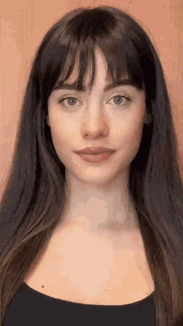 a woman with long dark hair and bangs is wearing a black shirt