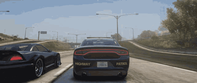 a highway patrol car drives down a highway next to another car