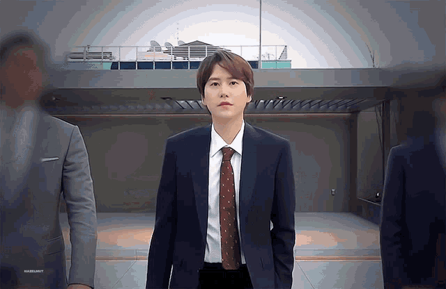 a man in a suit and tie is standing in front of a building that says ' marlboro ' on the bottom
