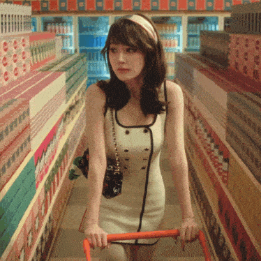 a woman in a white dress is pushing a shopping cart in a grocery store