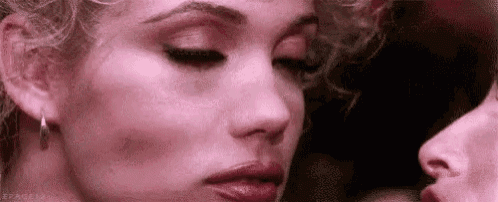 a close up of two women 's faces , one of whom is kissing the other .