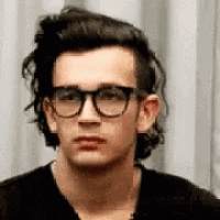 a young man wearing glasses and a black shirt .