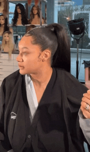 a woman is getting her hair done in a salon wearing a jacket that says aveda