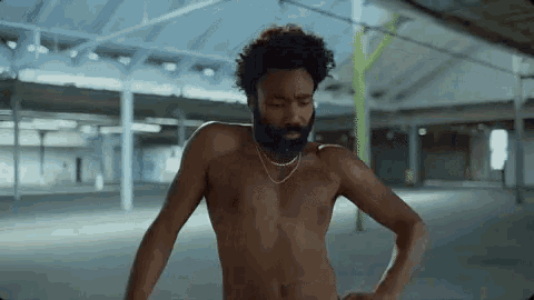 a shirtless man with a beard is standing in an empty building