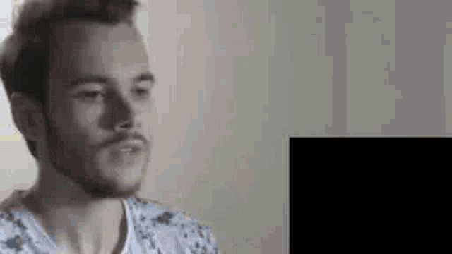 a man with a beard is talking to someone while wearing a floral shirt .