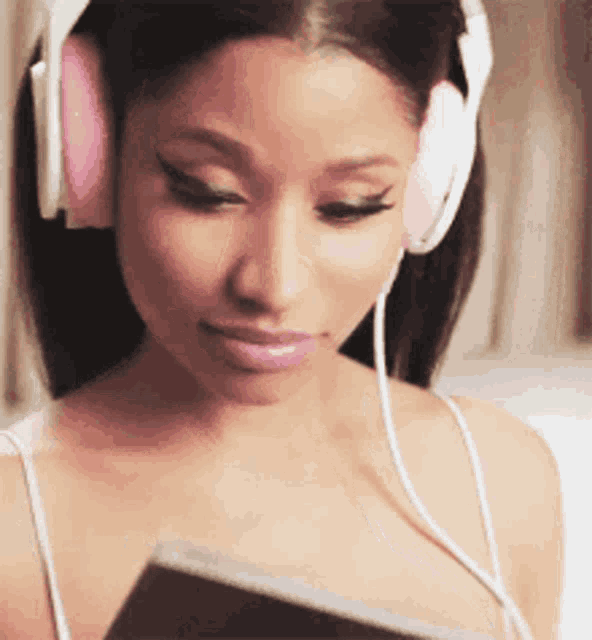a woman wearing headphones is listening to music and looking at a book .