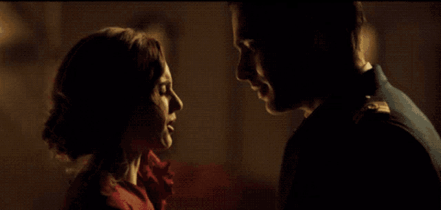 a man and woman are looking at each other in a dark room