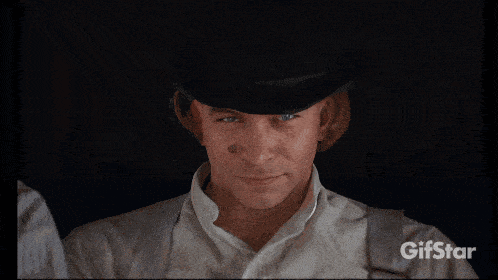 a man in a bowler hat is drinking milk from a carton