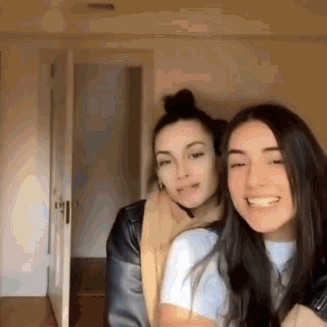 two young women are posing for a picture in a room and smiling .