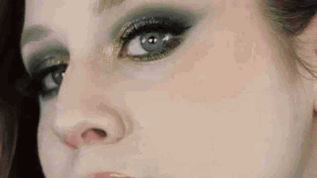 a close up of a woman 's face with green eye shadow and gold glitter .