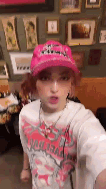 a girl wearing a pink hat and a t-shirt is taking a selfie .