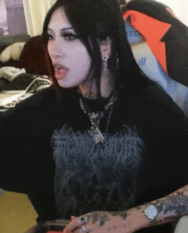 a woman wearing a black t-shirt with a skull on it is sitting in a chair