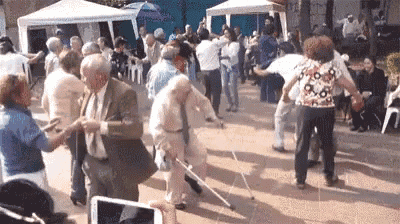 a group of elderly people are dancing on the sidewalk .