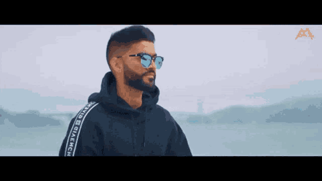 a man with a beard is wearing sunglasses and a hoodie .