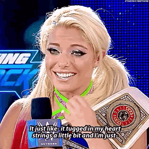 a woman is holding a championship belt and smiling while talking into a microphone