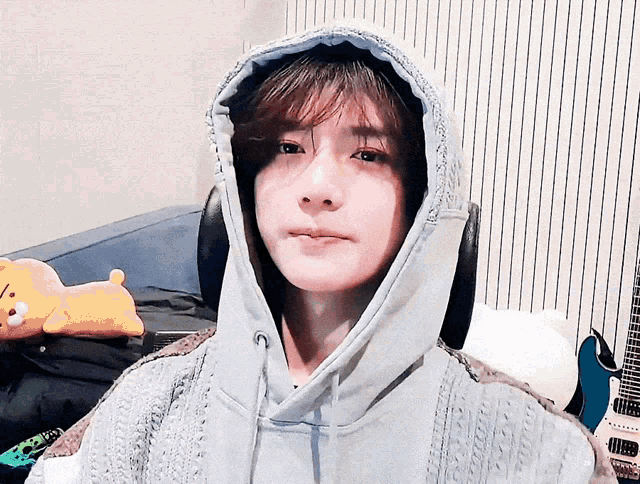 a woman wearing a hoodie and headphones is sitting on a couch