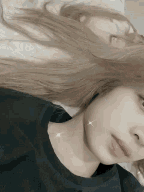 a woman with long blonde hair is laying on a bed and taking a selfie .