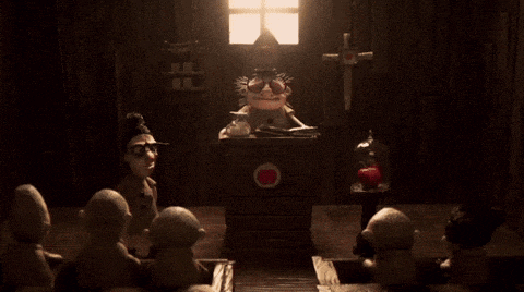 a group of cartoon characters are sitting around a table with a cross on it
