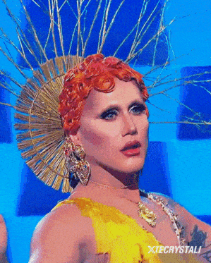 a drag queen wearing a yellow dress and a gold headpiece