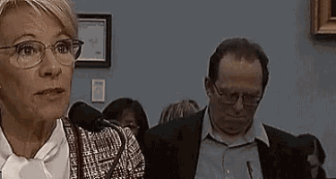 a woman wearing glasses stands next to a man wearing a suit .