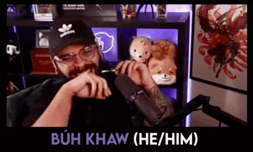 a man sitting in front of a microphone with the words buh khaw ( he / him ) on the bottom