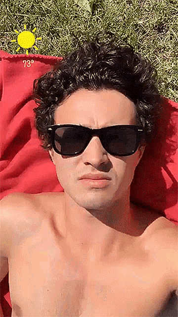 a shirtless man wearing sunglasses is laying in the sun