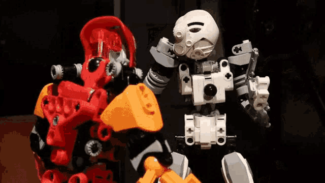 two lego robots are standing next to each other on a table .
