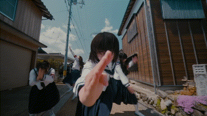 a girl in a school uniform is giving the middle finger while walking down a street