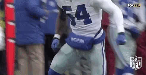a football player with the number 54 on his jersey is running with a fanny pack on his waist .