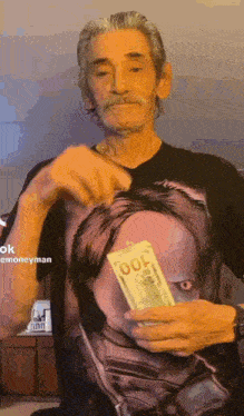 a man in a t-shirt with a picture of a woman on it is holding a stack of money .