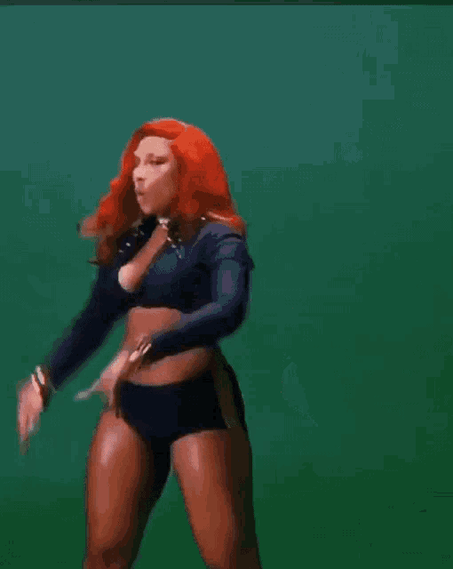 a woman with red hair is wearing a crop top and shorts .