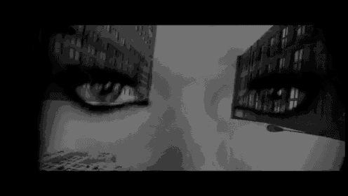 a black and white photo of a woman 's eyes with a building behind them