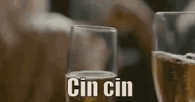 two glasses of beer are sitting on a table with the words cin cin written on the bottom .