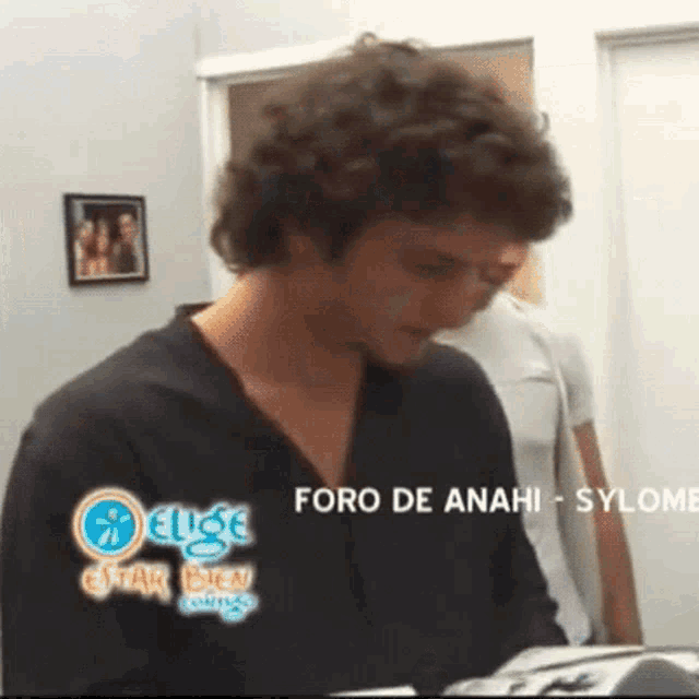 a man in a black shirt stands in front of a sign that says foro de anahi sylome