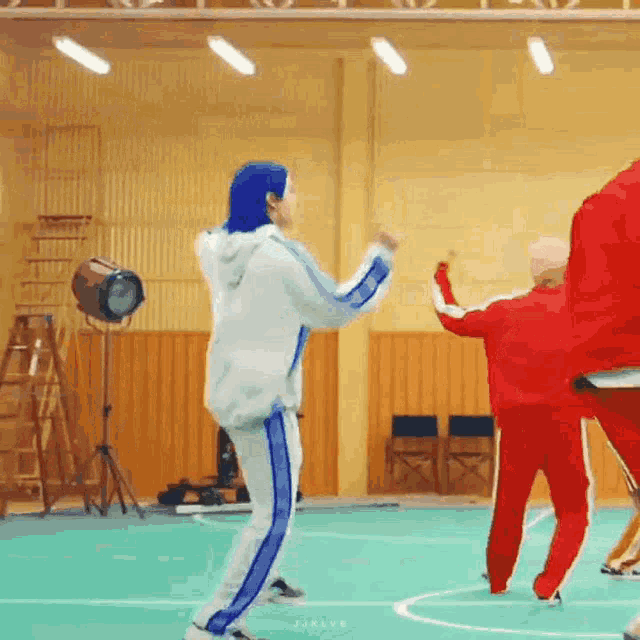a group of people are dancing on a green court in a gym .