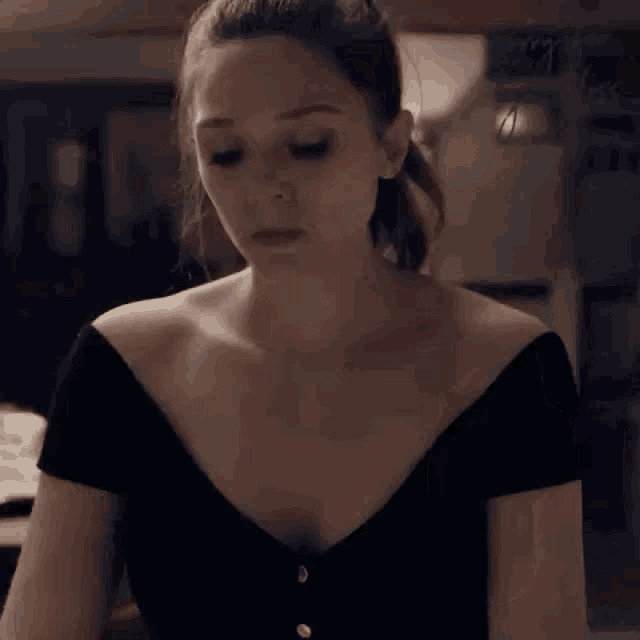 a woman in a black top is sitting at a table with a glass of wine .