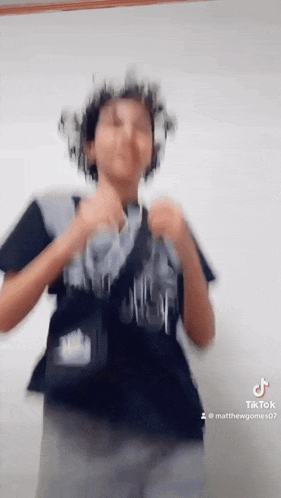 a blurry picture of a person wearing a black shirt and a gray backpack .