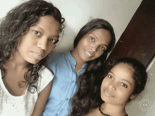 three young women are posing for a picture and one has a flower on her neck