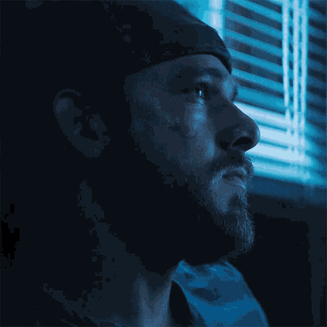 a man with a beard is looking out of a window