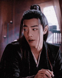 a man with long hair and a ponytail is wearing a black jacket and a kimono .