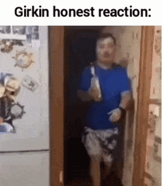 a man is standing in a doorway holding a bottle of alcohol and making a funny face .