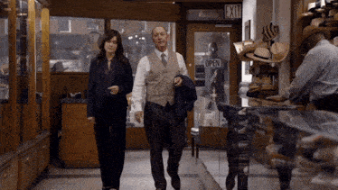 a man and a woman are walking in a store with an exit sign above them