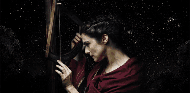 a woman in a red dress is playing a harp in front of a starry sky