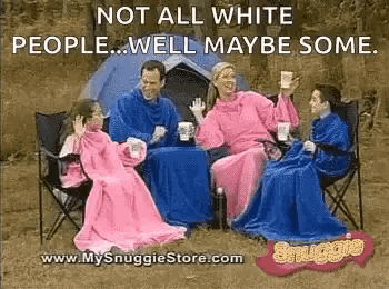 a family is sitting around a table with blankets on their arms .