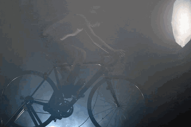 a person riding a bike in a dark room with a light behind them