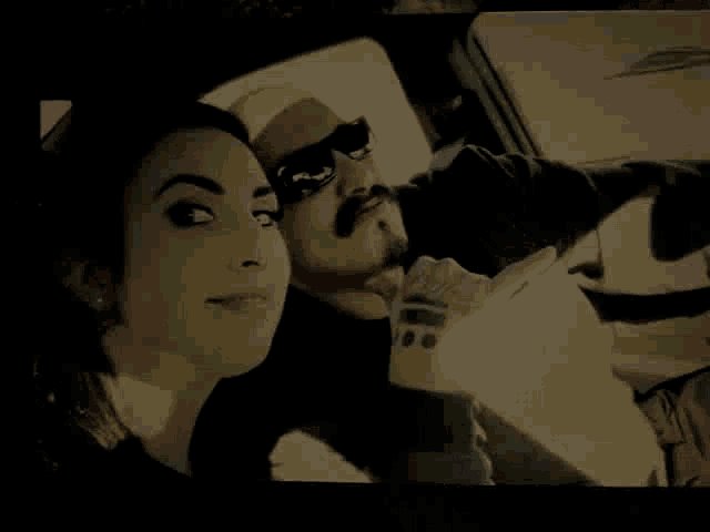 a man and a woman are in a car and the man is wearing sunglasses