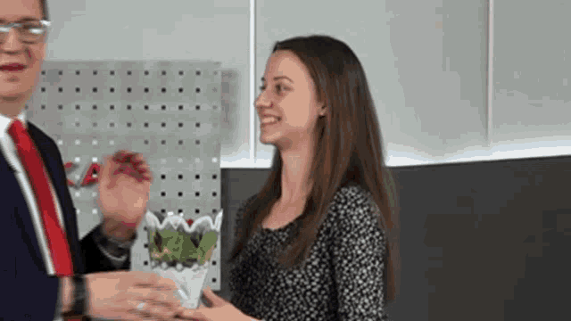 a man in a suit and tie is giving a woman a gift