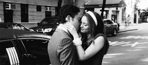 a man and a woman are kissing in front of a limousine on the street .