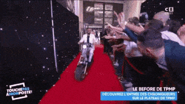 a man is riding a motorcycle on a red carpet in front of a crowd .
